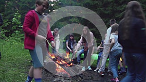 Teens playing having fun near campfire.