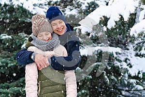 Teens portrait in a winter forest, boy and girl, beautiful nature with bright snowy fir trees