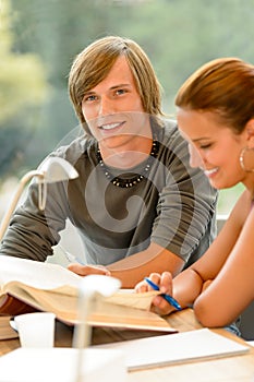 Teens reading book studying in high-school library