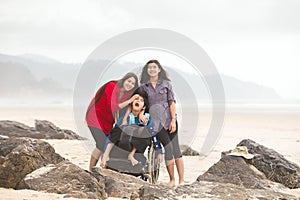 Teens sisters on beach with disabled little brother in wheelchair