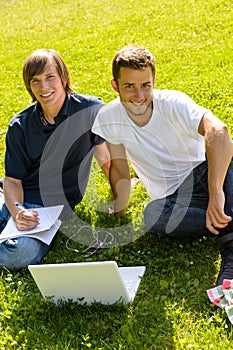 Teens sitting in park with laptop students