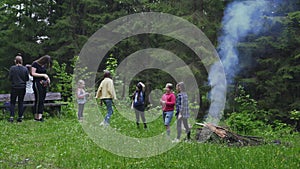 Teens talking near campfire.