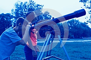 Teens with a telescope in the evening. Children looking with interest in the sky