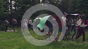 Teens using mats as umbrellas in forest.