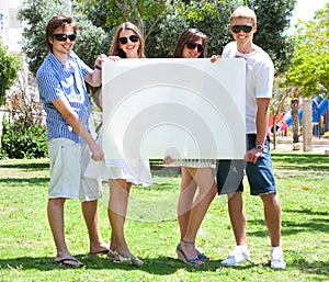 Teens with white billboard standing in park