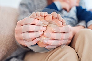 Teeny tiny little toes. Closeup shot of a mother holding her little baby boys feet.