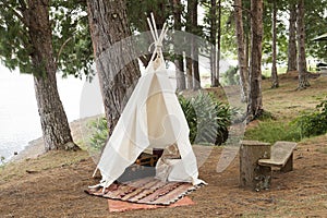 A teepee tent made of raw cloth in the middle of the forest