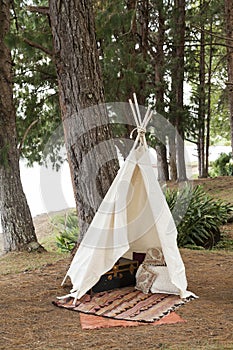 A teepee tent made of raw cloth in the middle of the forest