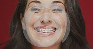 Teeth braces. Dental care for healthy smile. Orthodontic treatment. Close-up female smiling on red studio background