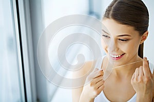 Teeth Care. Beautiful Smiling Woman Flossing Healthy White Teeth