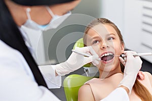 Teeth checkup at dentist's office. Dentist examining girls teeth