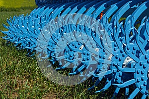 Teeth and knots of a rotary harrow standing on the grass
