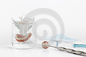 Teeth on mirror next to dentures in water