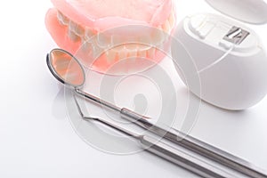 Teeth model with dental floss and mouth mirror on white background