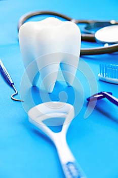 Teeth model and dentist tools on blue background.