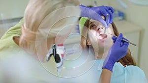 Teeth treatment in dental clinic. Dentist using dental tools to sick tooth
