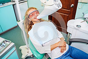 Teeth whitening. A patient in protective glasses from the rays in the chair at the dentist. Preventive examination of the oral