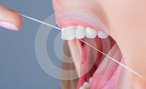 Teeths Flossing. Oral hygiene and health care. Smiling women use dental floss white healthy teeth. Dental flush - woman
