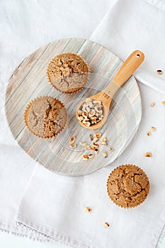 Teff hazelnut muffins on a plate with a scooper filled with hazelnuts.