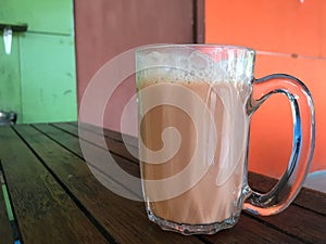 Teh with milk in a mug or popularly known as Teh tarik on the table. Malaysian favorite drink