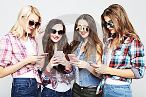 Tehnology, emotion and people concept: four happy women friends sharing social media in a smart phone