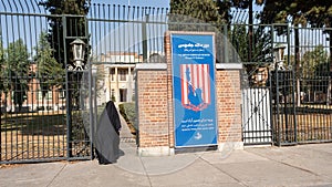 Woman in hijab walking near main entrance to the former US Embassy in Tehran, Iran