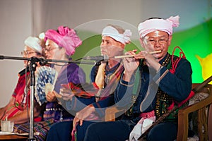 Tei old male minority with traditional clothes playing a bamboo flute.