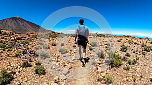 Teide - Man on hiking trail to summit Riscos de la Fortaleza with scenic view on volcano Pico del Teide photo