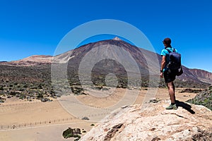 Teide - Man on rock with view on La Canada de los Guancheros dry desert plain and volcano Pico del Teide photo