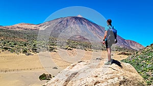 Teide - Man on rock with view on La Canada de los Guancheros dry desert plain and volcano Pico del Teide photo