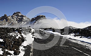 Teide National Park or Las Canadas del Teide in winter, views towards the road covered in snow and low white clouds passing by