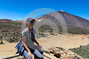 Teide - Woman on rock with view on La Canada de los Guancheros dry desert plain and volcano Pico del Teide