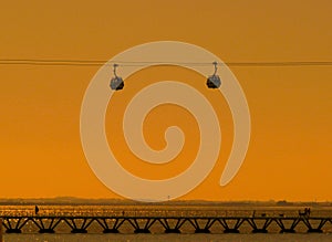 Telecabines cable cars at sunrise and people walking by the Tagus river at Park of Nations Parque das Nacoes, in Lisbon,