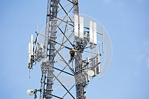 Telecom maintenance. Two repair men climbing on tower against blue sky background