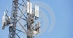 Telecom maintenance. Two repair men climbing on tower against blue sky background