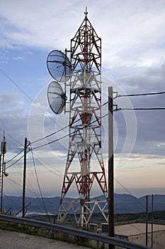 A telecom tower with two parabolic antennas with pylon carrying cables. It uses a parabolic reflector, a curved surface with the c