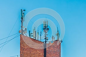 Telecommunication brick tower with mobile wireless antennas on blue sky background