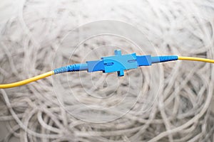 Telecommunication concept. Two yellow fiber optic wires are connected to each other with an optical adapter. Cable connection in