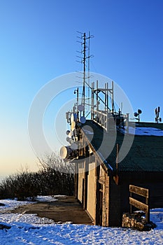 Telecommunication and microwave antennas and dishes installed on upper station of aricable. Evening sunlight and blue skies during