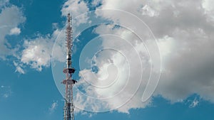 Telecommunication radio tower on the vast blue sky background. White clouds on sky