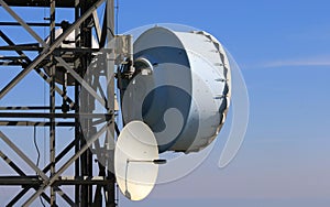 Telecommunication technology on a steel mast with a blue sky.