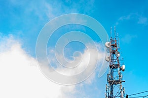 Telecommunication tower antenna with blue sky and cloud background