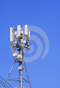 Telecommunication tower with antenna and equipment for cellular communication system against blue clear sky background