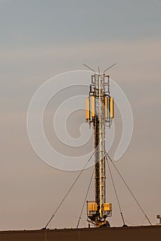 Telecommunication tower with cellular network antenna against blue sky as background