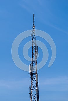 Telecommunication tower with cellular network antenna against blue sky as background