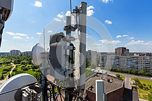 Telecommunication tower or mast with microwave, radio panel antennas, outdoor remote radio units, power cables, coaxial