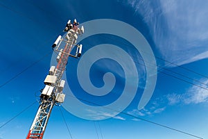 Telecommunication tower or mast with microwave, radio panel antennas, outdoor remote radio units, power cables, coaxial