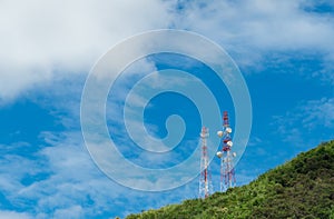 Telecommunication tower on mountain and green tree with blue sky. Antenna on blue sky. Radio and satellite pole. Communication