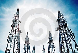 Telecommunication towers with TV antennas and satellite dish on clear blue sky