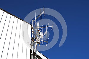 Telecommunication towers with TV antennas and satellite dish on clear blue sky